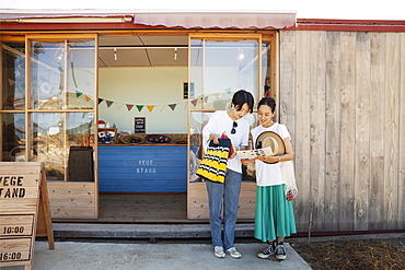 Two smiling Japanese women standing outside a farm shop, Kyushu, Japan