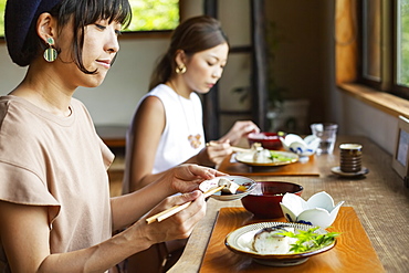 Two Japanese women sitting at a table in a Japanese restaurant, eating, Kyushu, Japan