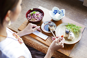 High angle view of Japanese woman sitting at a table in a Japanese restaurant, eating, Kyushu, Japan