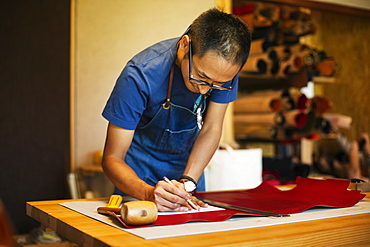 Japanese man wearing blue apron working in a leather shop, Kyushu, Japan