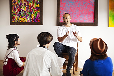 Group of Japanese men and women sitting in art gallery, holding a discussion, Kyushu, Japan