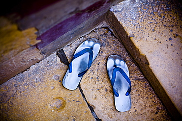 High angle close up of pair of worn down blue sandals outside on a doorstep, India, Rajasthan