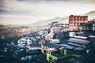 High angle view across a sprawling mountainside village under a cloudy sky, India