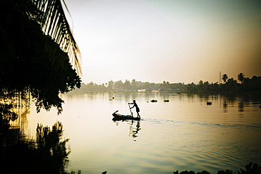 Local fisherman rowing a boat on a river in the early morning hours, Vietnam