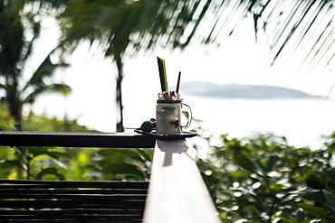 Close up of a "Tom Yum" cocktail with coconut-infused liquour standing a balustrade of balcony, Thailand