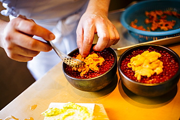 High angle close up of chef preparing uni, sea urchin, with salmon roe and rice, Japan