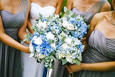 High angle view of bride and bridesmaids holding blue and white flower bouquets, Thailand