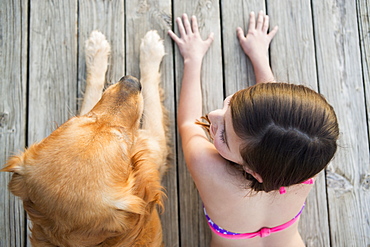 A young girl and a golden retriever dog side by side on a jetty, Austin, Texas, USA