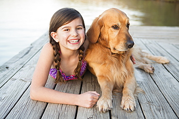 A young girl and a golden retriever dog lying on a jetty, Austin, Texas, USA