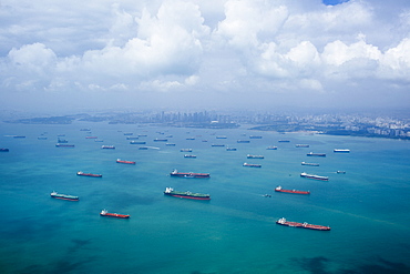 High angle view of barges and cargo ships in a bay, cityscape in the distance, Singapore