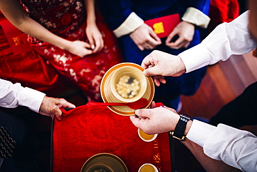 High angle close up of a ritual at a Chinese wedding ceremony, people passing a bowl of soup