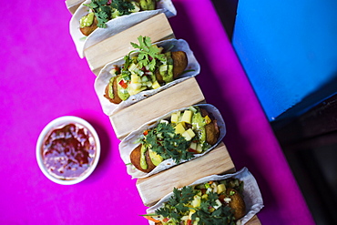 High angle close up of Baja fish tacos on a pink table, Vietnam