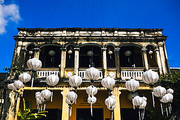 Traditional white lanterns hanging in front of an historic building, Vietnam