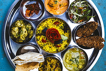 High angle close up of traditional Indian lunch with rice, various curries, pickles, and vegetables, India