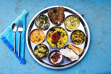 High angle close up of traditional Indian lunch with rice, various curries, pickles, and vegetables, India