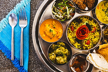 High angle close up of traditional Indian lunch with rice, various curries, pickles, and vegetables, India