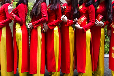 Close up of line of young women in traditional red and yellow dress outside of a wedding, Vietnam