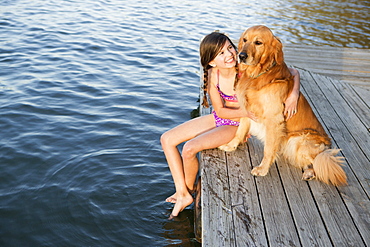 A girl and her golden retriever dog seated on a jetty by a lake, Austin, Texas, USA