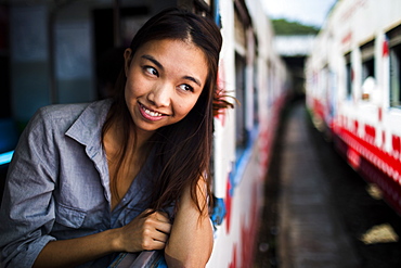 Smiling young woman riding on a train, looking out of window, Myanmar