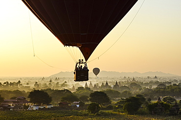 Hot air balloon over landscape with temples at sunset, Bagan, Myanmar