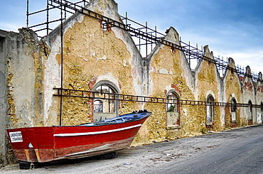 Red boat lying on street lined with dilapidated buildings, Lisbon, Portugal