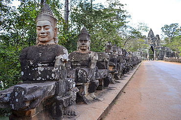 Ankor Wat, a 12th century historic Khmer temple and UNESCO world heritage site. Busts and statues of deities and guardian figures along a path to a stupa and entrance arch, Angkor Wat, Cambodia