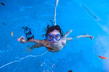 A boy swimming underwater in a pool with goggles, St Simon's Island, Georgia, United States