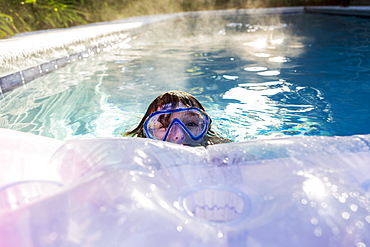 A six year old boy playing in a heated pool, St Simon's Island, Georgia, United States