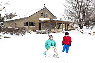 A boy and girl sledding down hill in snow, United States