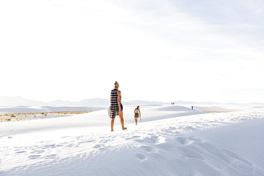 Woman walking in white sand dunes, White Sands National Monument, New Mexico, United States