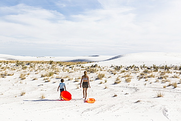 Two children pulling sledges, White Sands National Monument, New Mexico, United States