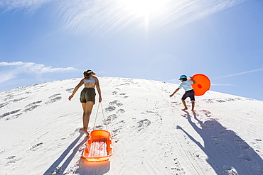 A brother and sister, boy and girl climbing a sand dune, White Sands National Monument, New Mexico, United States