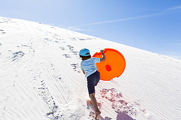 A young boy climbing sand dune, White Sands National Monument, New Mexico, United States