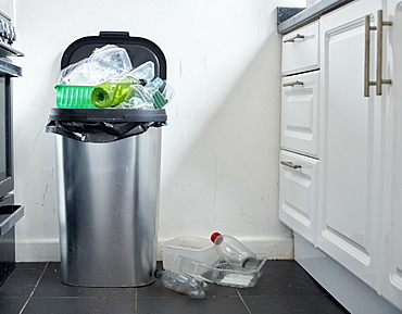 Various used plastic containers overflowing from dustin in kitchen, Bristol, United Kingdom