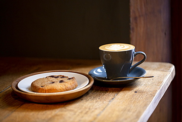 Close up of cup of Cappuccino and chocolate chip cookie on a plate in a cafe