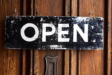 Close up of black and white open sign on wooden door of a cafe