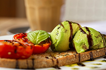 Close up of tomato and avocado bruschetta with balsamic vinegar reduction in a cafe