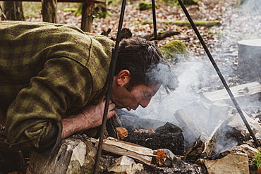 Man starting a camp fire in a forest, Devon, United Kingdom