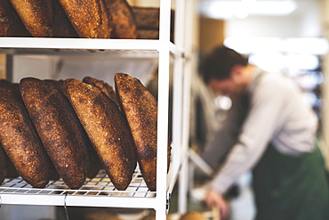 Artisan bakery making special sourdough bread, racks of bread and a baker in the background