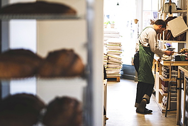 Artisan bakery making special sourdough bread, racks of bread and a baker in the background