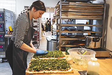 A baker making a savoury loaf, pressing herbs and fillings into dough