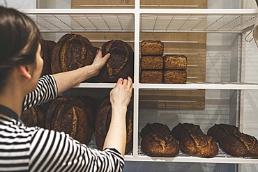 Artisan bakery making special sourdough bread, baker loading shelves with baked goods