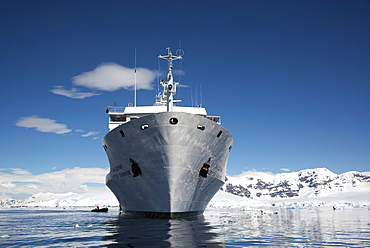 An Antarctic cruise ship with inflatable zodiacs on the calm waters among ice floes and mountainous landscape, Antarctic peninsula, Antarctica