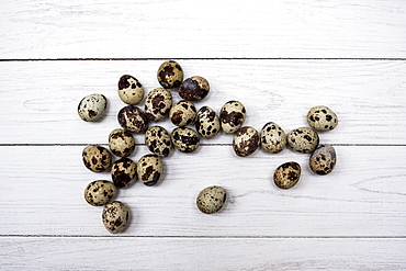 High angle close up of quail eggs on white wooden table