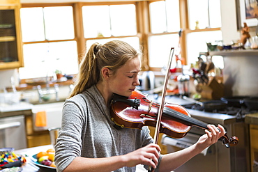 13 year old girl playing violin at home