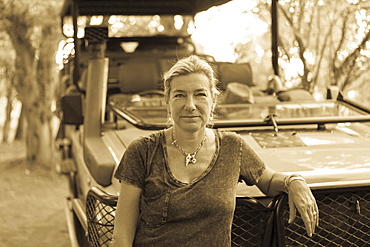 Portrait of woman leaning on a safari vehicle, Moremi Game Reserve, Botswana