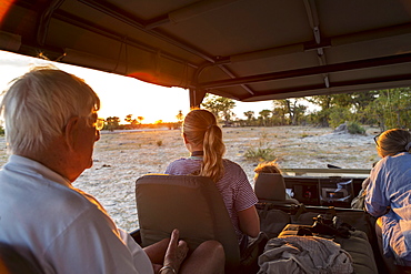 Three generations of a family on safari, in a jeep out at sunset, Moremi Game Reserve, Botswana