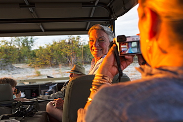 Senior woman in a jeep turning and smiling for the camera, Moremi Game Reserve, Botswana