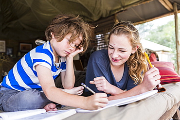 Brother and sister doing homework together in a tented camp in Botswana