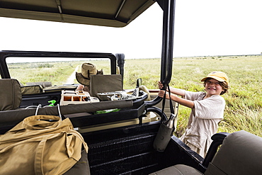 Six year old boy holding onto a safari vehicle leaning out